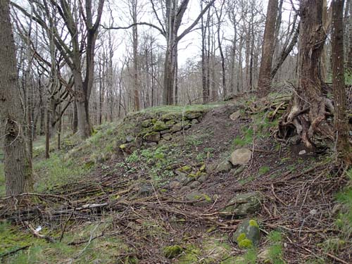 Murar för att stärka sluttningens kanter är idag de enda spåren av husen. Foto: Per Hallén 2014.